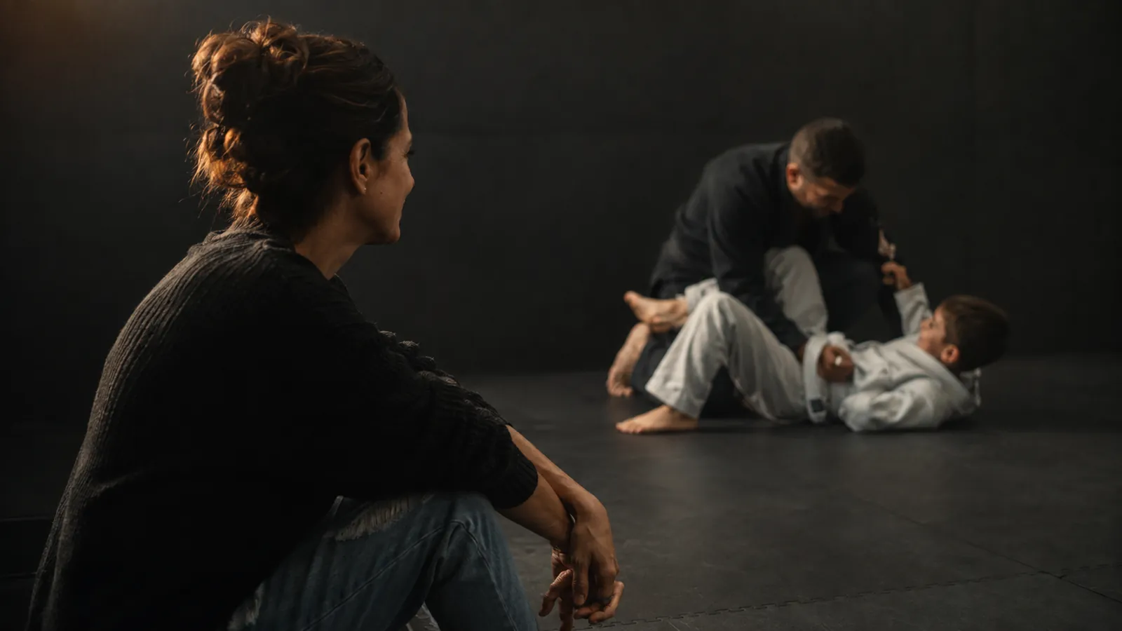 A parent watching from the mat's edge while their child trains